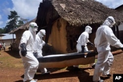 FILE - Health workers carry the body of a woman suspected of contracting the Ebola virus in Bomi county situated on the outskirts of Monrovia, Liberia, Oct. 20, 2014.