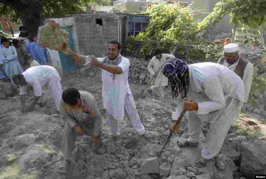 Earthquake survivors stand on the rubble of a mud house after it collapsed in Jalalabad province, Afghanistan, April 24, 2013. 