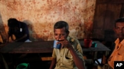 FILE - A Sri Lankan man drinks toddy, the sap of coconut palm, in a improvised neighborhood bar in Colombo, Sri Lanka.