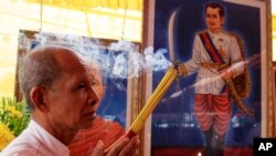 Cambodian man holds the burned incense sticks in front of a painted photo of a Kampuchea Krom Hero, Son Kuy, right, at a ceremony in Phnom, file photo. 