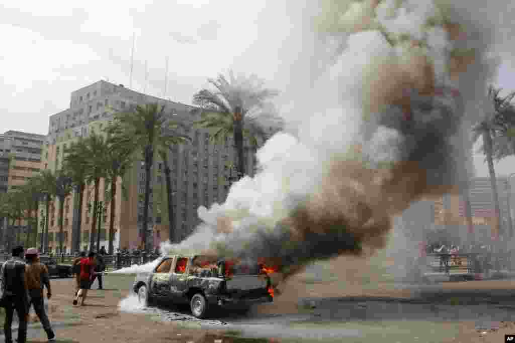 Người Ai Cập tìm cách dập tắt chiếc xe bị đốt gần quảng trường Tahrir ở Cairo. Gần hai năm sau khi đòi dân chủ, Ai Cập vẫn còn xáo trộn, biểu tình.