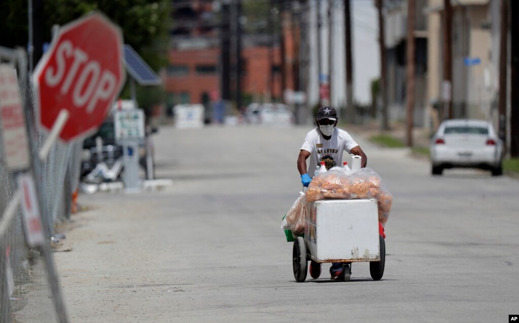 Texas: Un vendedor de helados empuja su carrito a través de una calle desolada en San Antonio. San Antonio permanece bajo una orden de quedarse en casa.