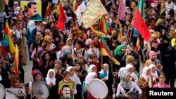 FILE - Protesters carry pictures of Abdullah Ocalan, the jailed leader of the Kurdistan Workers' Party (PKK), during a demonstration in support of Kurdish fighters and the besieged Syrian town of Kobani, in Aleppo, Syria, Nov. 1, 2014. 