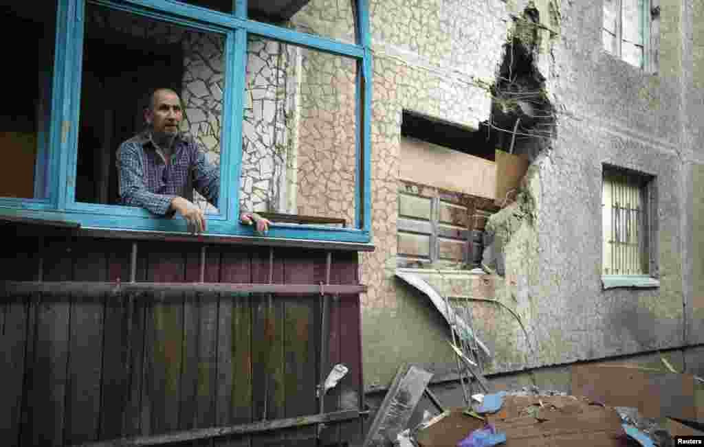 A man looks out of a window of his apartment, which was damaged by shelling, in Slovyansk in eastern Ukraine, June 30, 2014.
