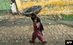 FILE - 60 year old manual scavenger Kela carrying a basket of human excrement her head after cleaning toilets in Nekpur village, Muradnagar in Uttar Pradesh, some 40 kms east of New Delhi, August 10, 2012.
