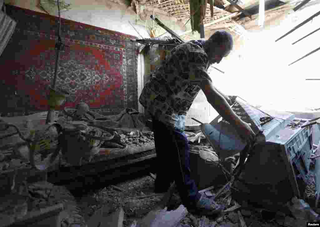 A man searches through the debris of his house, ruined during recent shelling in Donetsk, Aug. 12, 2014.