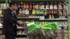 A man pushes a shopping cart past a display of nuts imported from the United States and other countries at a supermarket in Beijing, April 2, 2018. 