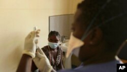FILE - A young woman prepares to get vaccinated against COVID-19 at a health facility in Harare, Zimbabwe, Sept, 24, 2021.