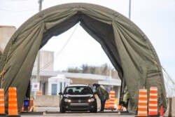FILE -:Travelers arriving from the United States enter a tent erected to perform the coronavirus molecular test at one of five initial entry points, at the Champlain-St. Bernard de Lacolle Border Crossing in Quebec, Canada, Feb. 24, 2021.