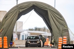 FILE -:Travelers arriving from the United States enter a tent erected to perform the coronavirus molecular test at one of five initial entry points, at the Champlain-St. Bernard de Lacolle Border Crossing in Quebec, Canada, Feb. 24, 2021.
