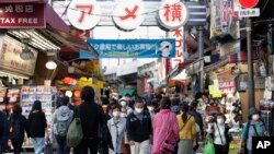 Warga mengenakan masker saat berjalan melintasi persimpangan lalu lintas di Tokyo, Kamis, 19 November 2020. (AP Photo/Hiro Komae)
