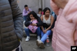 FILE - Migrants wait outside the Mexican Commission for Refugee Aid government office to apply for asylum in Mexico City, Jan. 28, 2025.