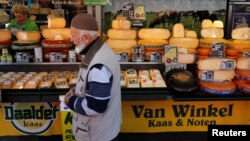 FILE - A man walks by a cheese stall at a market in The Hague, Netherlands.