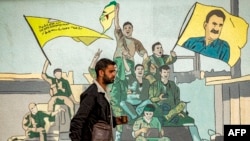 A man walks past a mural depicting supporters of the Syrian Democratic Forces, one of them raising a flag showing the face of Abdullah Ocalan — founding member of the militant Kurdistan Workers' Party, which is outlawed by Turkey, in Qamishli, Syria, on Dec. 16, 2024.