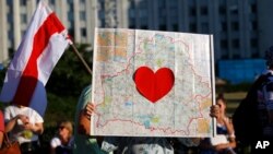 FILE - A protester holds up a map of Belarus with a red heart during an opposition rally challenging presidential election results in Minsk, Belarus, Aug. 17, 2020. Belarusian photojournalist Alyaksandr Zyankou went on trial Friday on charges linked to work covering protests. 