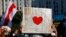 FILE - A protester holds up a map of Belarus with a red heart during an opposition rally challenging presidential election results in Minsk, Belarus, Aug. 17, 2020. Belarusian photojournalist Alyaksandr Zyankou went on trial Friday on charges linked to work covering protests. 