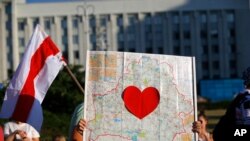 FILE - A protester holds up a map of Belarus with a red heart inside, during an opposition rally challenging official presidential election results, in front of a government building in Minsk, Belarus, Aug. 17, 2020.