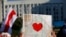 FILE - A protester holds up a map of Belarus with a red heart inside, during an opposition rally challenging official presidential election results, in front of a government building in Minsk, Belarus, Aug. 17, 2020.