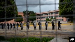 ARCHIVO - En esta fotografía del 26 de septiembre de 2015, la policía hace guardia alrededor del edificio del Congreso estatal, mientras la gente pasa fuera de la cerca, algunos gritando burlas y lanzando piedras, en el primer aniversario del Ayotzinapa, en Chilpancingo, México.