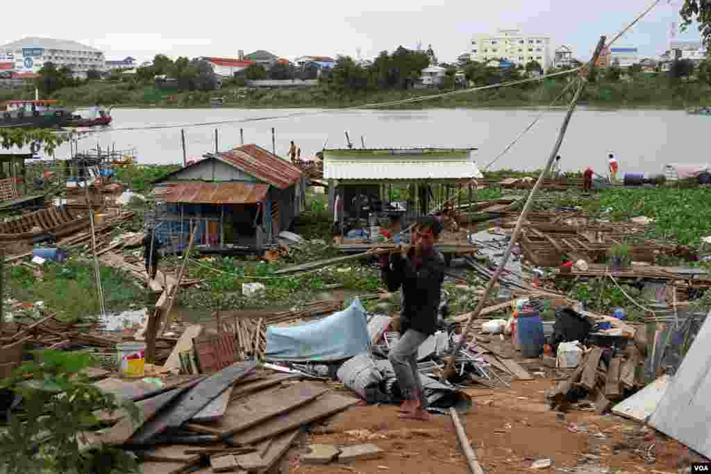 A man moves pieces of board after authorities told him to dismantle a floating house in Prek Pra commune, Chbar Ampov district, Phnom Penh, June 12, 2021. (Vicheika Kann/VOA)