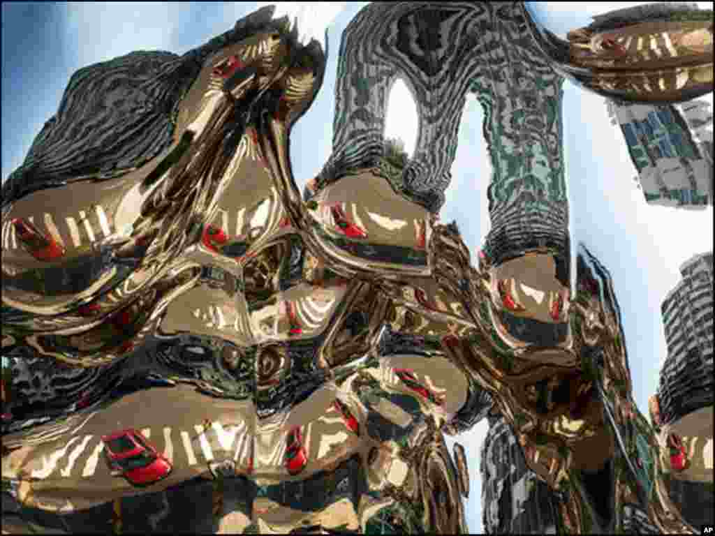 بیجنگ کے شاپنگ مال کے باہر لگے آرٹ کے نمونے پر عمارتوں اور کاروں کا عکس