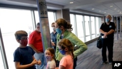 FILE - People wearing masks wait to board a flight in Kansas City, Mo., May 24, 2020. Governments and businesses are scrambling to change course following new federal guidance calling for the return of mask wearing in virus hot spots.