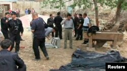 Police and government officials stand near the bodies of victims following a bloody clash in Bachu, Xinjiang, April 23, 2013. 