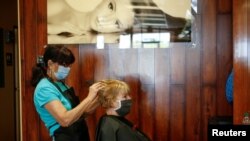 Donna Ferraro corta el cabello de Jan Campbell en una sala de belleza, durante la fase de reapertura tras las restricciones impuestas por el coronavirus en Cave Creek, Arizona.