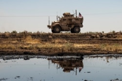 A US armoured vehicle drives past an oil field in the countryside of al-Qahtaniyah town in Syria's northeastern Hasakeh province near the Turkish border, on Aug. 4, 2020.