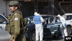 TOPSHOT - Tim penyelamat dan pasukan keamanan Israel bekerja di lokasi serangan di dekat desa al-Funduq, di Tepi Barat yang diduduki, pada 6 Januari 2025. (GIL COHEN-MAGEN/AFP)