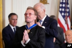 Bono gestures as President Joe Biden presents him with the Presidential Medal of Freedom, the nation's highest civilian honor, in the East Room of the White House in Washington, Jan. 4, 2025.