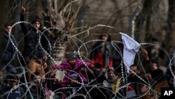 Migrants stand behind a fence near the Kastanies border gate at the Greek-Turkish border, March 2, 2020.