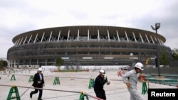FILE PHOTO: Workers are seen at the construction site of the New National Stadium, the main stadium of Tokyo 2020 Olympics and Paralympics, during a media opportunity in Tokyo, Japan July 3, 2019. REUTERS/Issei Kato/File Photo