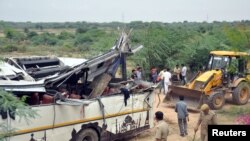 Polisi dan warga melihat badan bus yang rusak setelah tergelincir dan terperosok ke saluran air di pinggiran Agra, India, 8 Juli 2019. (Foto: Reuters)