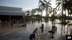 Habitantes de Acapulco caminan en un estacionamiento con el agua hasta la cintura en Punta Diamante, México.