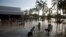 Habitantes de Acapulco caminan en un estacionamiento con el agua hasta la cintura en Punta Diamante, México.