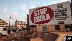 Des piétons passent une affiche de campagne contre la maladie à virus Ebola à Freetown, Sierra Leone, 15 janvier 2015