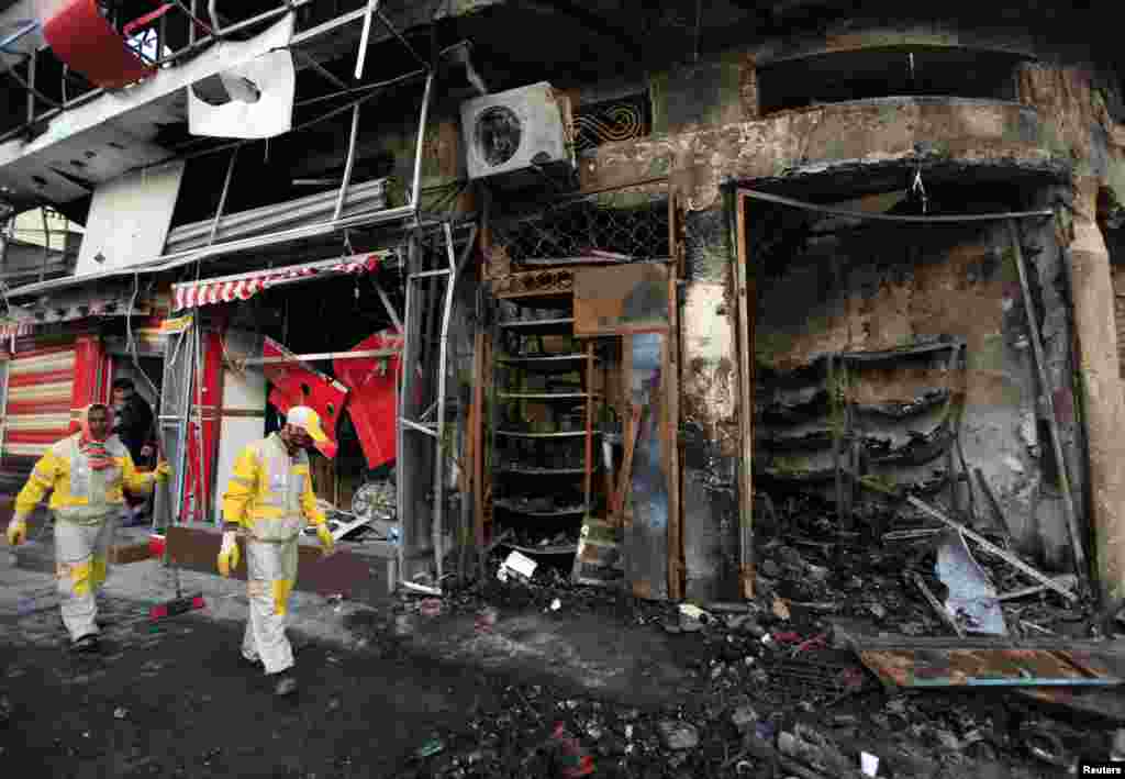 Staf pemerintah kota membersihkan puing-puing ledakan bom di lokasi serangan bom di distrik Karrada, Baghdad, 18 Februari 2014.