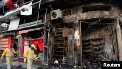 FILE - Municipal workers clean the site of a bomb attack in Baghdad's Karrada district, Feb. 18, 2014.