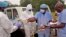 Health workers are handed personal protective gear by a team leader (R) before collecting the bodies of the deceased from streets in Monrovia, Liberia, Aug. 16, 2014.