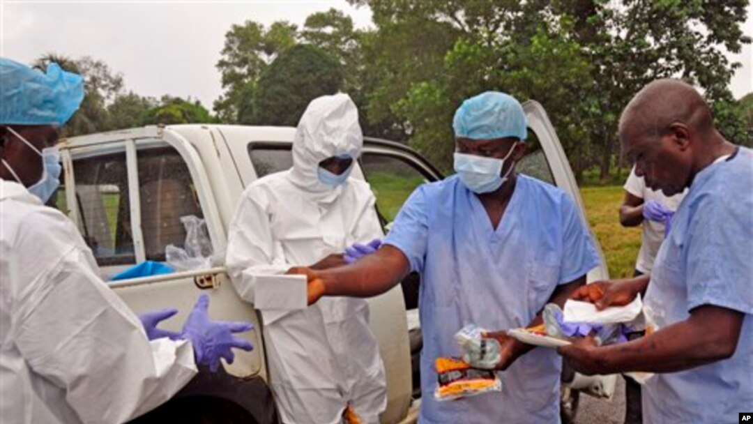 Health workers are handed personal protective gear by a team leader, right, before collecting the bodies of the deceased from streets in Monrovia, Liberia, Saturday, Aug. 16, 2014. New figures released by the World Health Organization showed that Liberia has recorded more Ebola deaths than any of the other affected countries. (AP Photo/Abbas Dulleh)