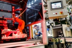 orIn this May 25, 2017, file photo, an assembly line laborer works alongside a collaborative robot at the Stihl Inc. production plant in Virginia Beach, Virginia.