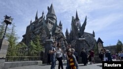 Guests pose before they enter Hogwarts School during a soft opening and media tour of "The Wizarding World of Harry Potter" theme park at the Universal Studios Hollywood in Los Angeles, California March 22, 2016. 