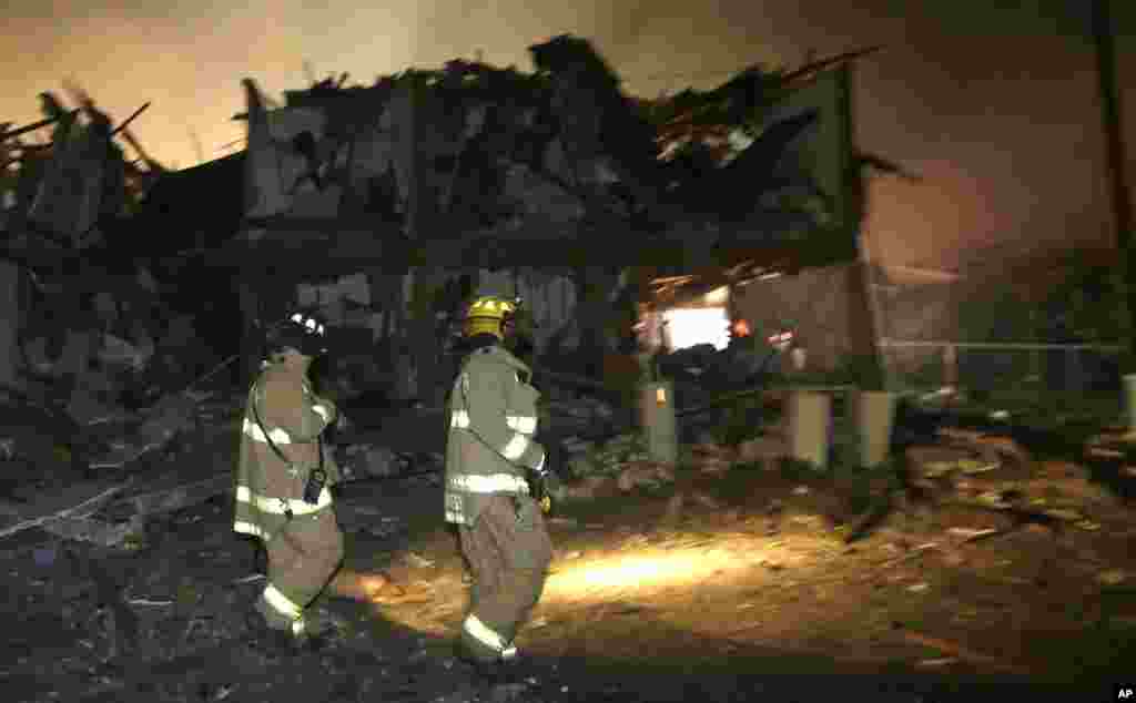 Para petugas pemadam kebakaran berjalan di dekat komplek hunian dekat pabrik pupuk yang hancur pasca ledakan pabrik tersebut, Kamis pagi, 18 April 2013. Pabrik pupuk di kota West, dekat Waco, Texas meledak Rabu malam, 17 April 2013.