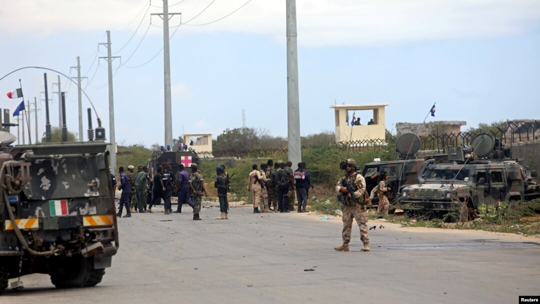Tentara Italia dan Somalia dekat kendaraan baja di lokasi penyerangan konvoi militer Italia, di Mogadishu, Somalia, 30 September 2019.