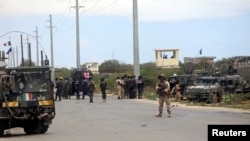 Tentara Italia dan Somalia dekat kendaraan baja di lokasi penyerangan konvoi militer Italia, di Mogadishu, Somalia, 30 September 2019.