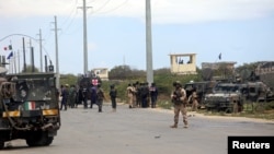 Italian and Somali security forces are seen near armored vehicles at the scene of an attack on a Italian military convoy in Mogadishu, Somalia, Sept. 30, 2019.