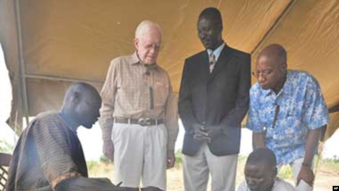 Feb. 11, 2010. Terekeka, Southern Sudan. Former U.S. President and Carter Center Founder Jimmy Carter watches while Garbino, a young farmer with a Guinea worm disease, receives free treatment from a village volunteer trained by The Carter Center in partne