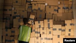 Un trabajador apila un remolque de envío con artículos en cajas para entregar en el centro de distribución de Amazon en Phoenix, Arizona.