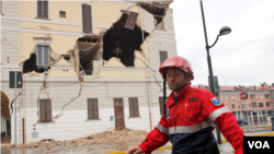 Seorang petugas penyelamat melewati gedung balaikota St. Agostino, wilayah Bologna yang rusak parah akibat gempa (20/5).